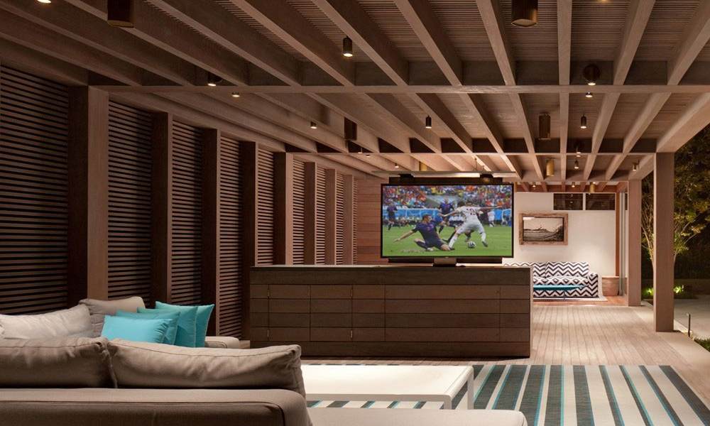 outdoor patio setting in the rain. A weather alert message shows on an outdoor TV.