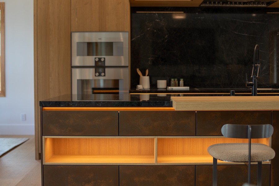 Warm, tunable LED lighting glowing beneath a kitchen island and shelves, supporting a human-centric lighting design