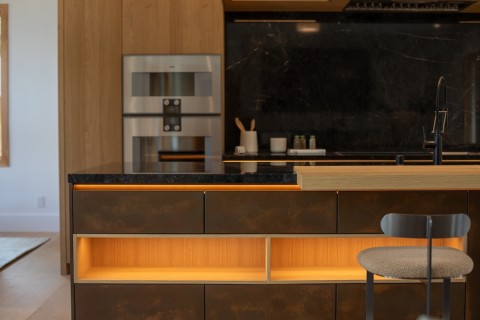 Warm, tunable LED lighting glowing beneath a kitchen island and shelves, supporting a human-centric lighting design