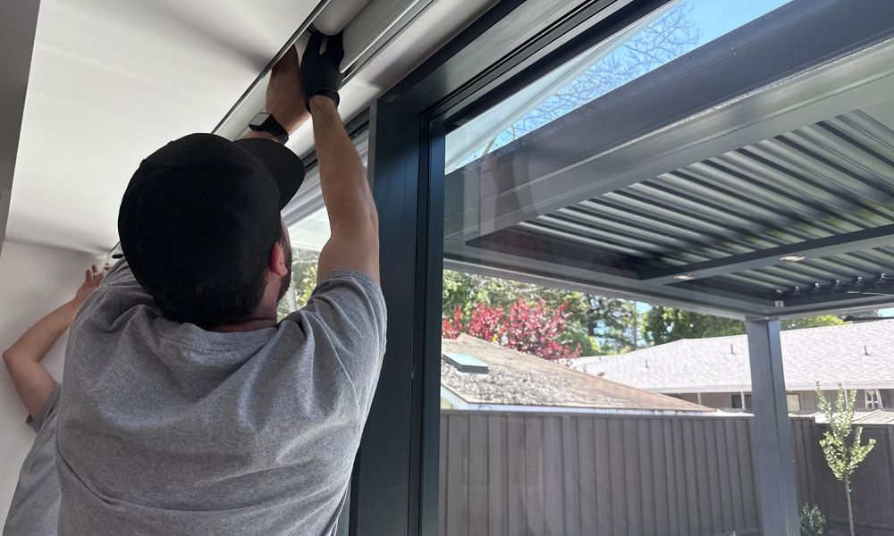 Close-up of a technician adjusting a white roller shade into a recessed ceiling track