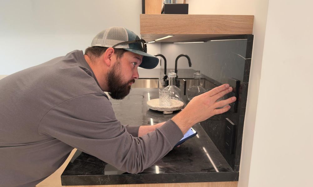 Technician adjusting a black smart switch above a black marble counter