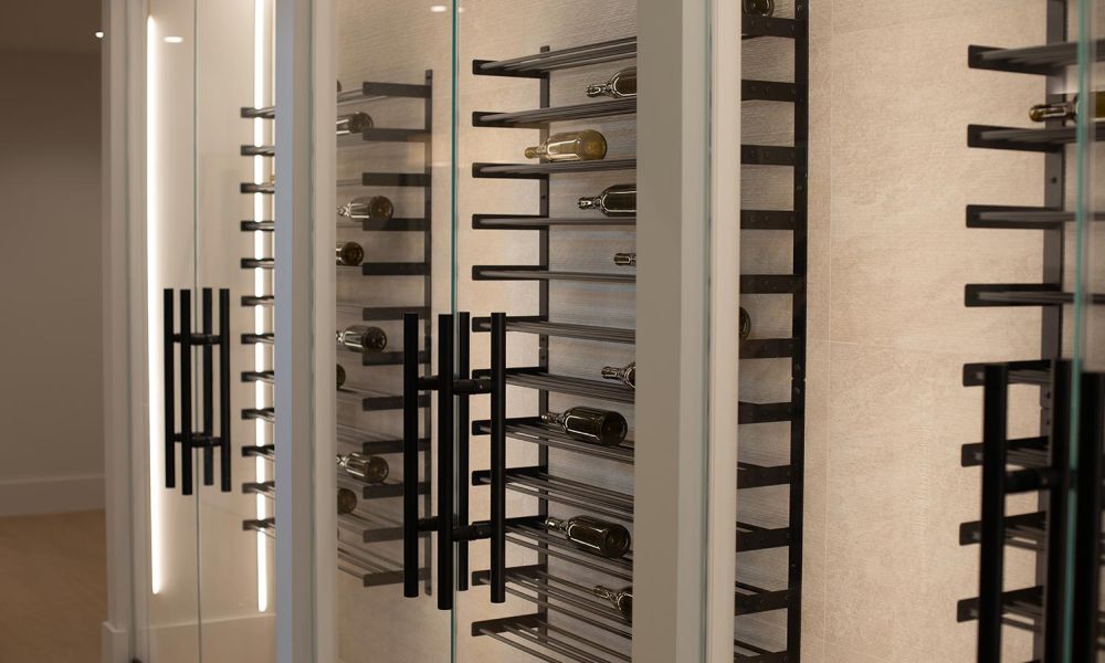 Interior wine cellar with black metal racks and glass doors, illuminated by vertical LED strips