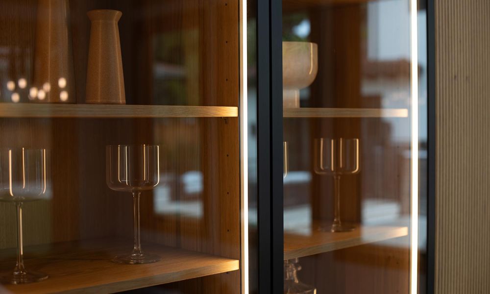 Close-up of a lit display cabinet with glass doors and LED strips highlighting drinkware and ceramics