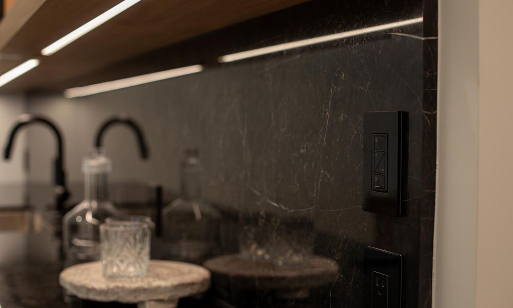 Black dimmer switch on black backsplash in a bar setting